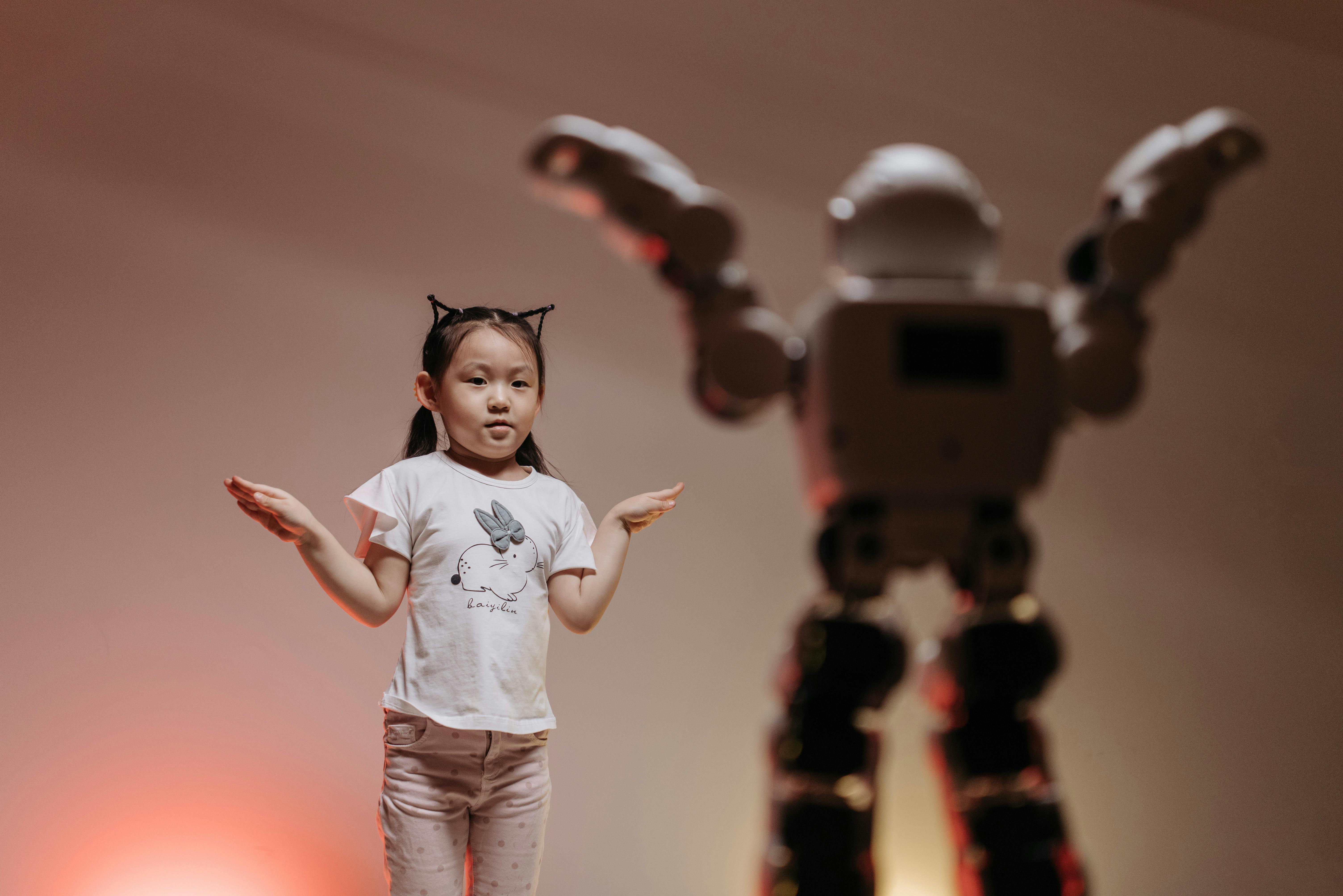 a robot imitating the pose of a young child (Photo by Pavel Danilyuk: https://www.pexels.com/photo/a-robot-imitating-a-girl-s-movement-8294811/)